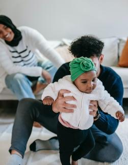 A young family plays with their toddler in their home. 